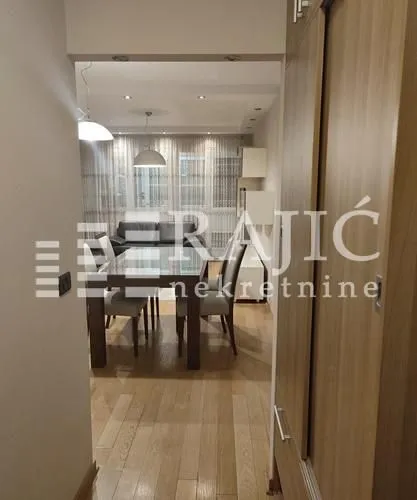 View from the hallway into the dining area and living room with hardwood floors.