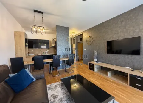 Modern living room with a sofa, TV, and dining area in an open-plan space. - image 3