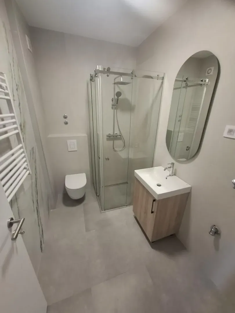 Moderno opremljeno kupatilo sa tuš kabinom, umivaonikom i WC šoljom.