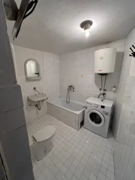 Kupatilo sa bijelim pločicama, kadom i veš mašinom. - image 5