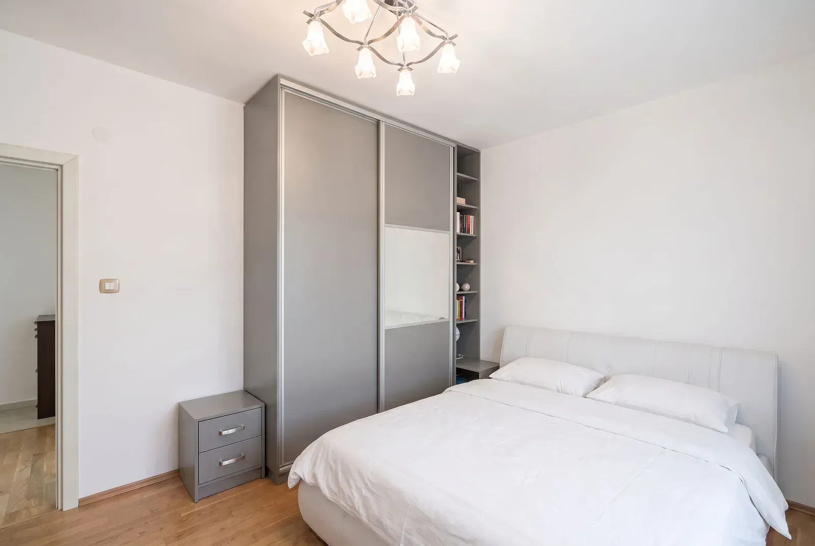 Bright bedroom with a large double bed, wardrobe, and nightstand.