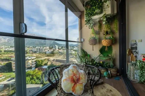 Zastakljeni balkon sa ukrasnim biljkama i pogledom na grad. - image 28