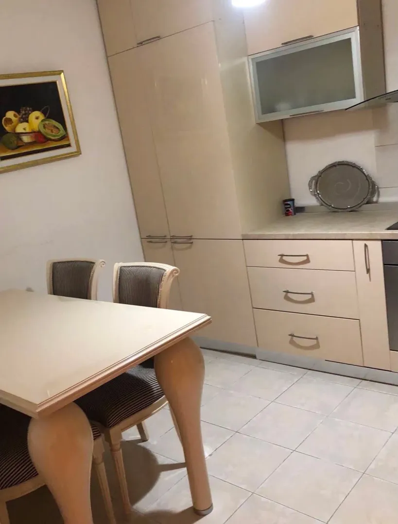 Kuhinja sa trpezarijskim stolom i ugradnim elementima.