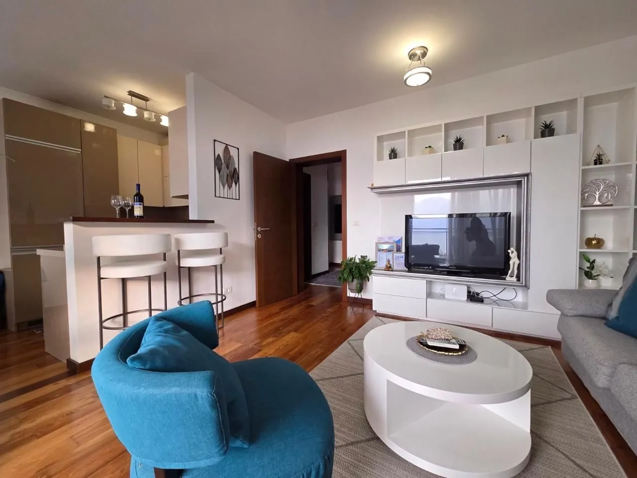 Spacious living room with seating area, TV, and dining space in the background.