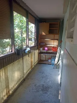 Zastakljeni balkon sa policama i pogledom na zelenilo. - image 6