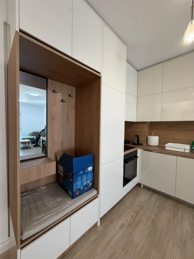 Moderna kuhinja sa bijelim elementima i drvenim detaljima.