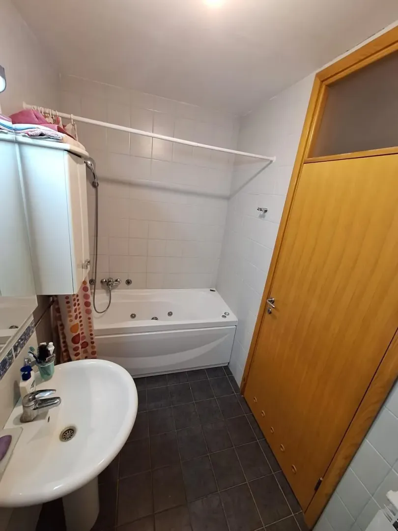 Kupatilo sa kadom, umivaonikom i drvenim vratima.