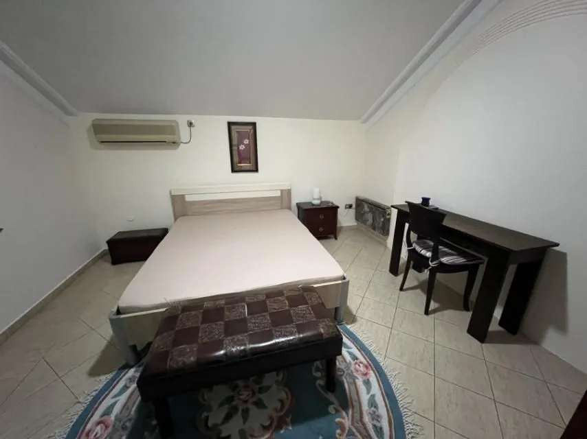 Simply furnished attic bedroom with a double bed and a desk.