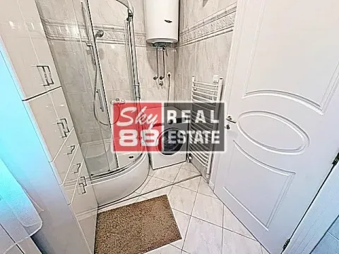 Bathroom equipped with a shower cabin, washing machine, and white cabinet. - image 7