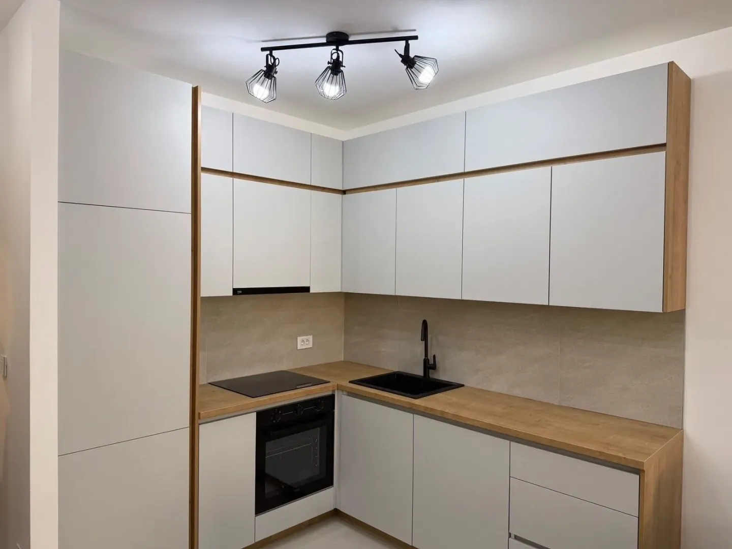 Modern kitchen with white cabinetry, wooden countertops, and built-in appliances.