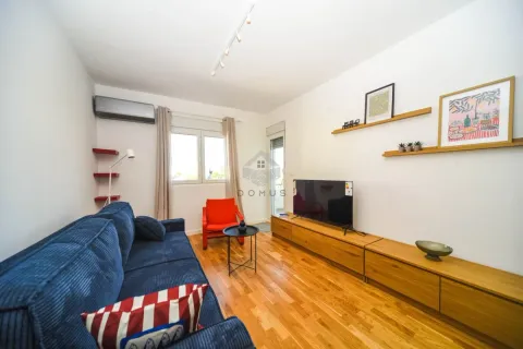 Living room with a blue sofa, TV, and wooden furniture. - image 12
