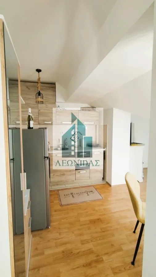 Small kitchen with wooden cabinets and a refrigerator inside the apartment.