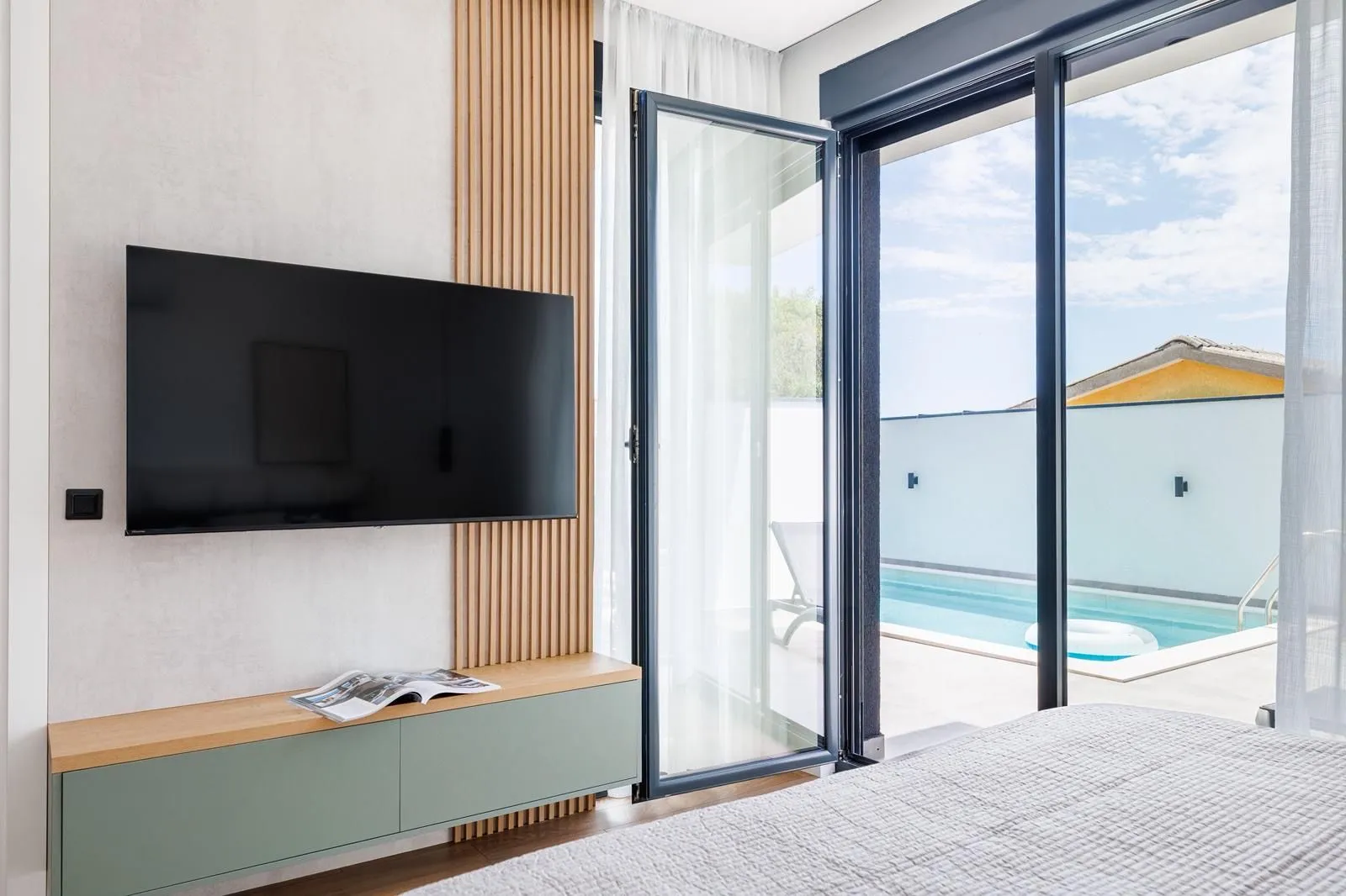 Modern bedroom with a view of the pool and access to the terrace.