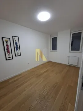 Prazna soba sa parketom na podu i umetničkim slikama na zidu. - image 6