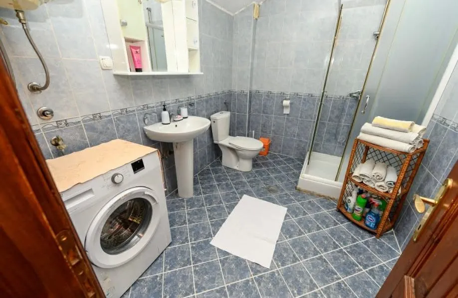 Tiled bathroom with a shower cabin, washbasin, and washing machine.