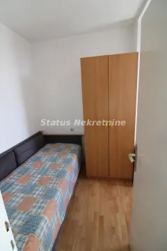 Manja spavaća soba sa krevetom i drvenim ormarom. - image 4