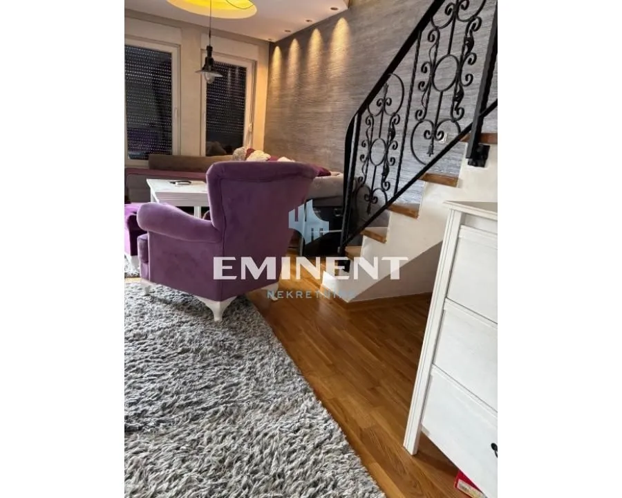 Living room with a purple armchair, sofa, and staircase.