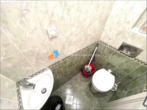 Small bathroom with a sink, toilet, and green tiles. - image 4