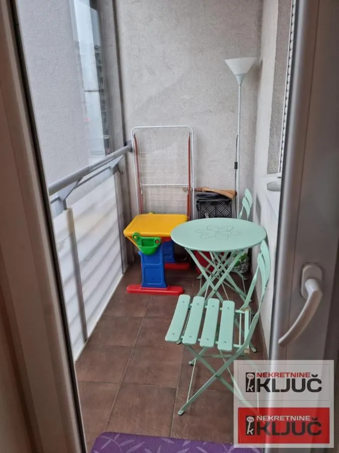 Manji namešteni balkonski prostor sa stolom, stolicama i sušilicom za veš.