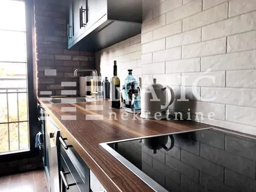 Modern kitchen with a wooden countertop and white brick wall.