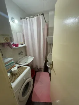 View of the bathroom with a sink, bathtub, washing machine, and toilet. - image 8