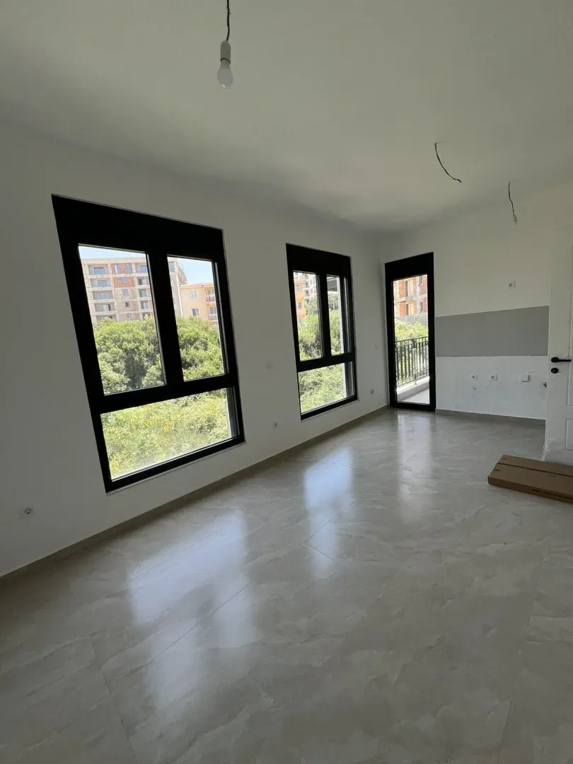 Bright empty room in a new building with large windows and tiled floors.
