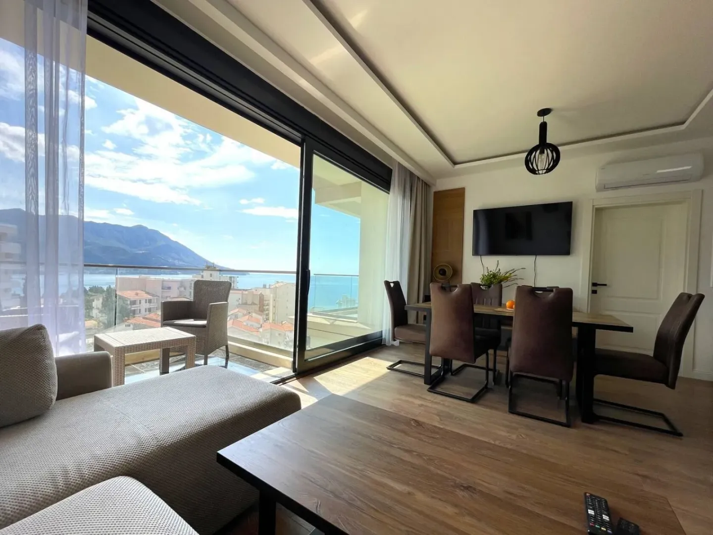 Living room with dining area and sea view through a large glass wall.