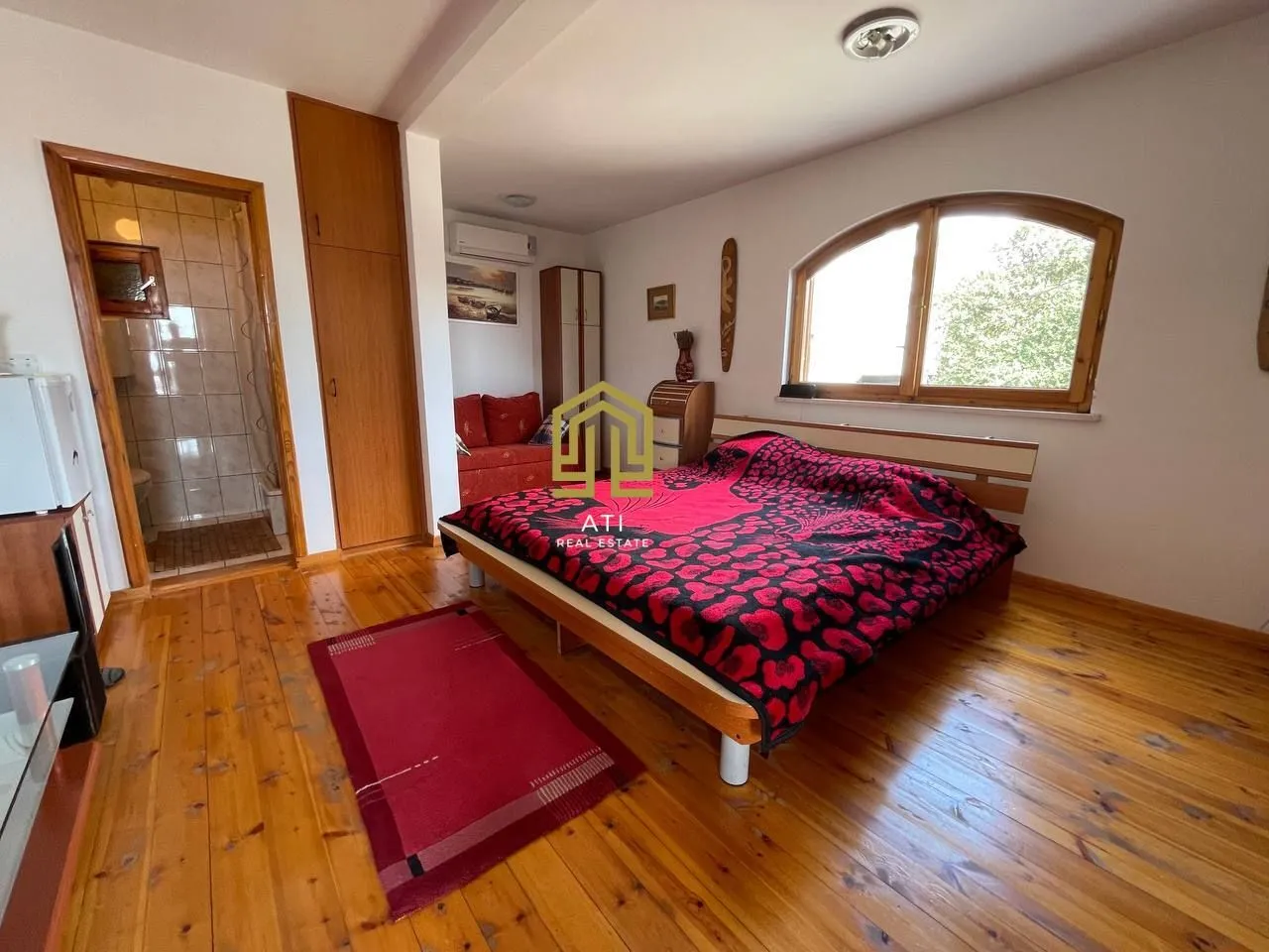 Bedroom with a double bed, wooden flooring, and an en-suite bathroom.