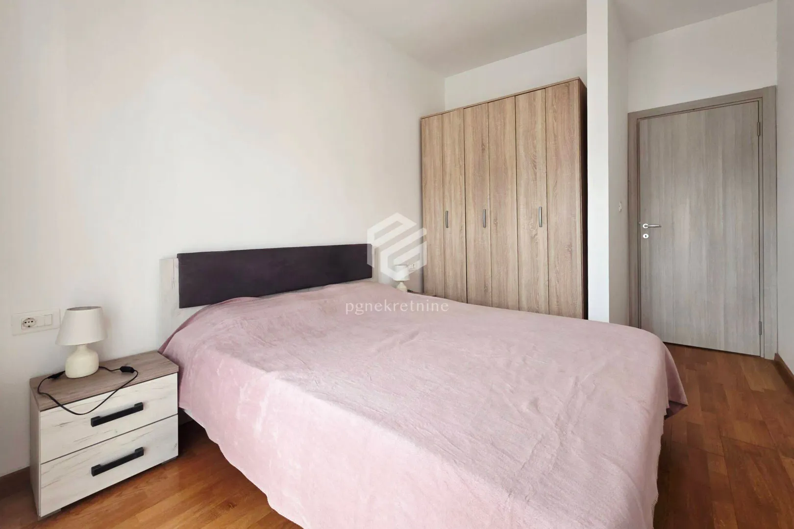 Bedroom with a double bed, nightstand, and wooden wardrobe.