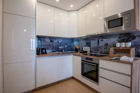Moderna bijela kuhinja sa drvenom radnom pločom i ugrađenim uređajima. - image 3