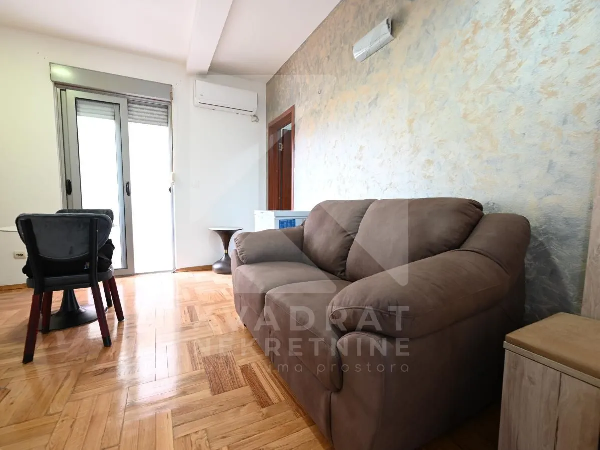 Living room with a brown sofa and a dining table by the balcony doors.