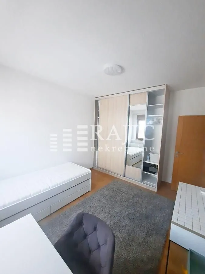Furnished bedroom with a bed, large wardrobe, and a desk.