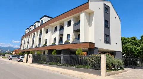 Pogled na spoljašnost moderne stambene zgrade sa uređenim dvorištem i ogradom. - image 5