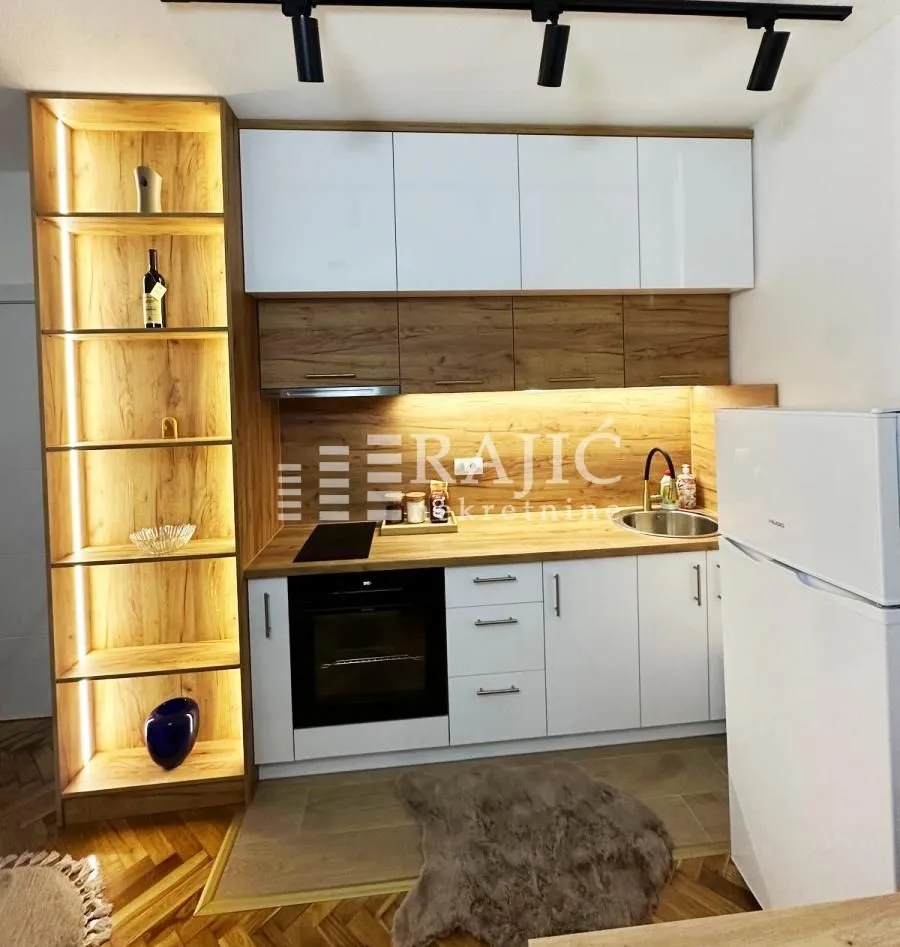 Modern kitchen with white cabinets, wood accents, and integrated lighting.