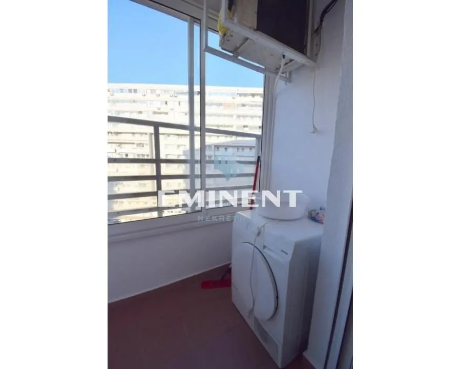 Enclosed balcony with a washing machine and air conditioning unit.