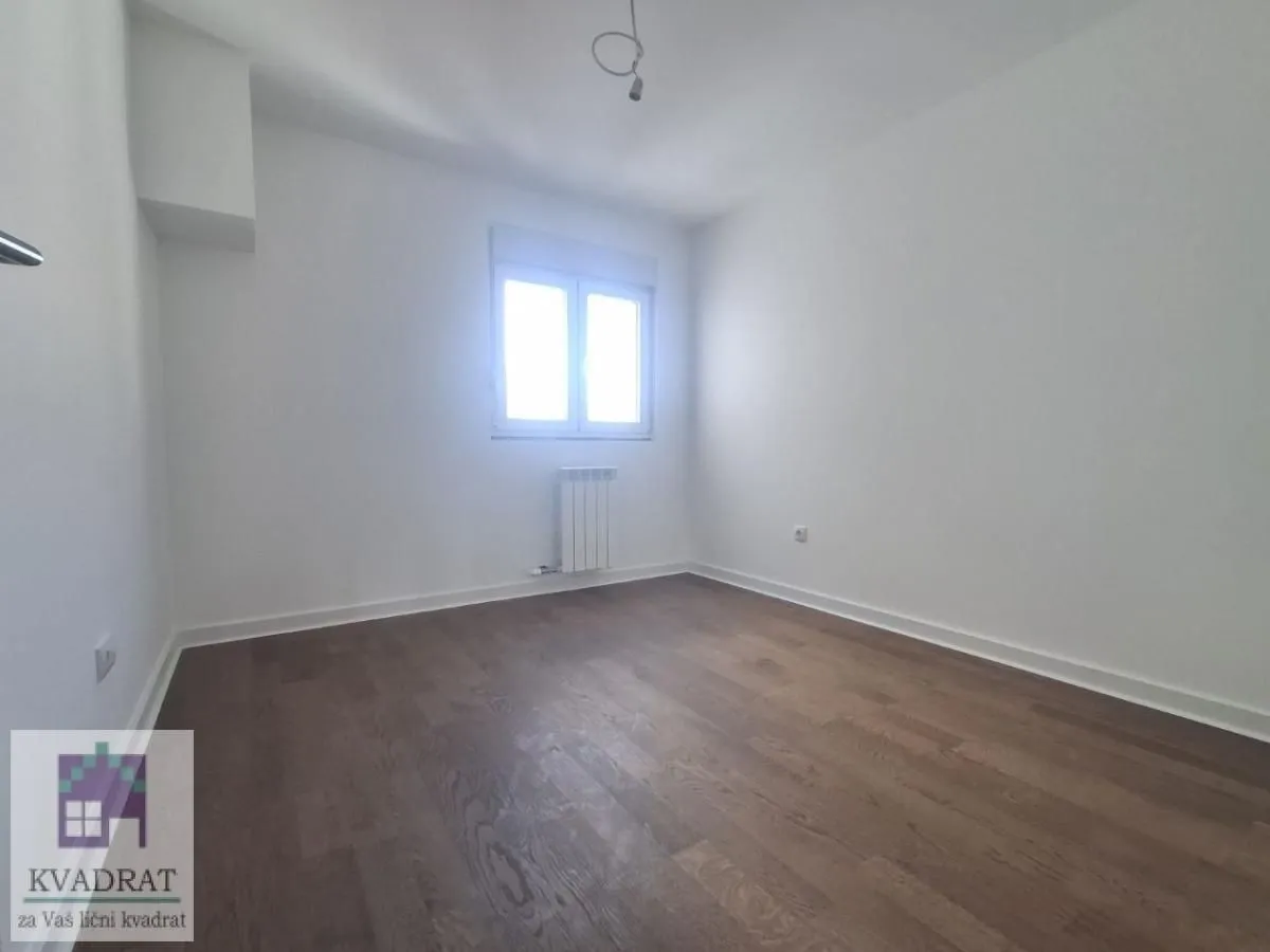 Empty room with white walls, wooden flooring, and a single window.