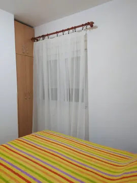 Bright bedroom with a colorful bedspread and a wooden wardrobe next to the window. - image 15