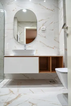 Modern bathroom equipped with a washbasin, mirror, and marble tiles. - image 13