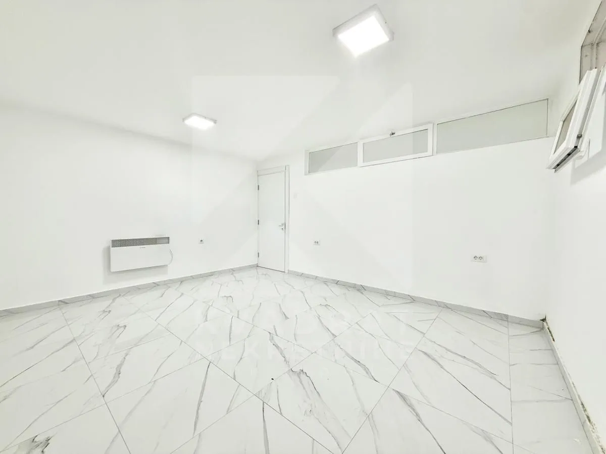 Empty bright room with white walls and marble tile flooring.