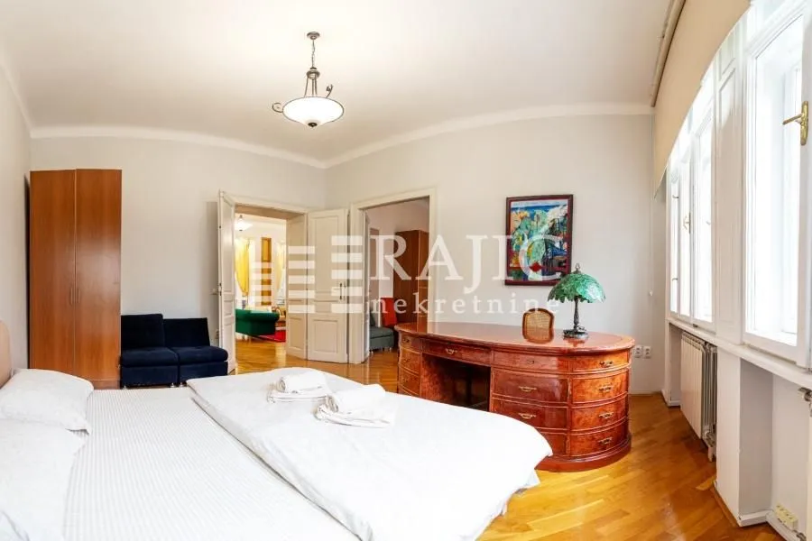 Spacious bedroom with a double bed, desk, and wooden flooring.