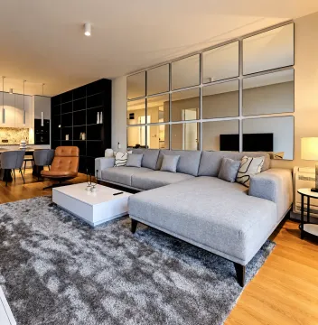 Modern living room with a sectional sofa, coffee table, and decorative wall mirrors. - image 9