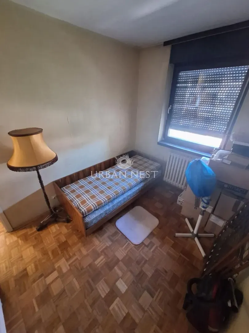 Small bedroom with a single bed, floor lamp, and a window.