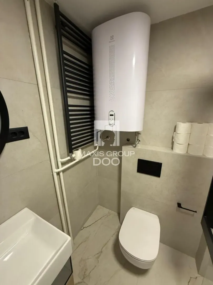 View of the bathroom with a toilet, washbasin, and water heater.