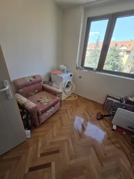 Manja soba sa parketom, foteljom i prozorom koji gleda na susedne zgrade. - image 14