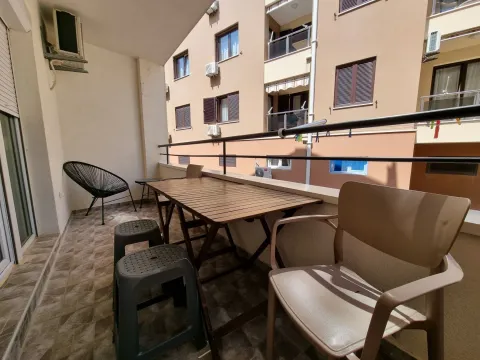 Namješten balkon sa stolom, stolicama i pogledom na okolnu zgradu. - image 3