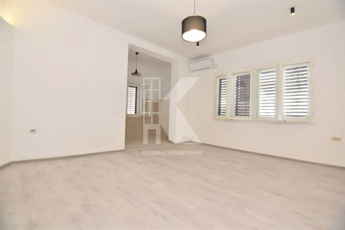 Empty living room with white walls, light flooring, and a view towards the passage to another room.