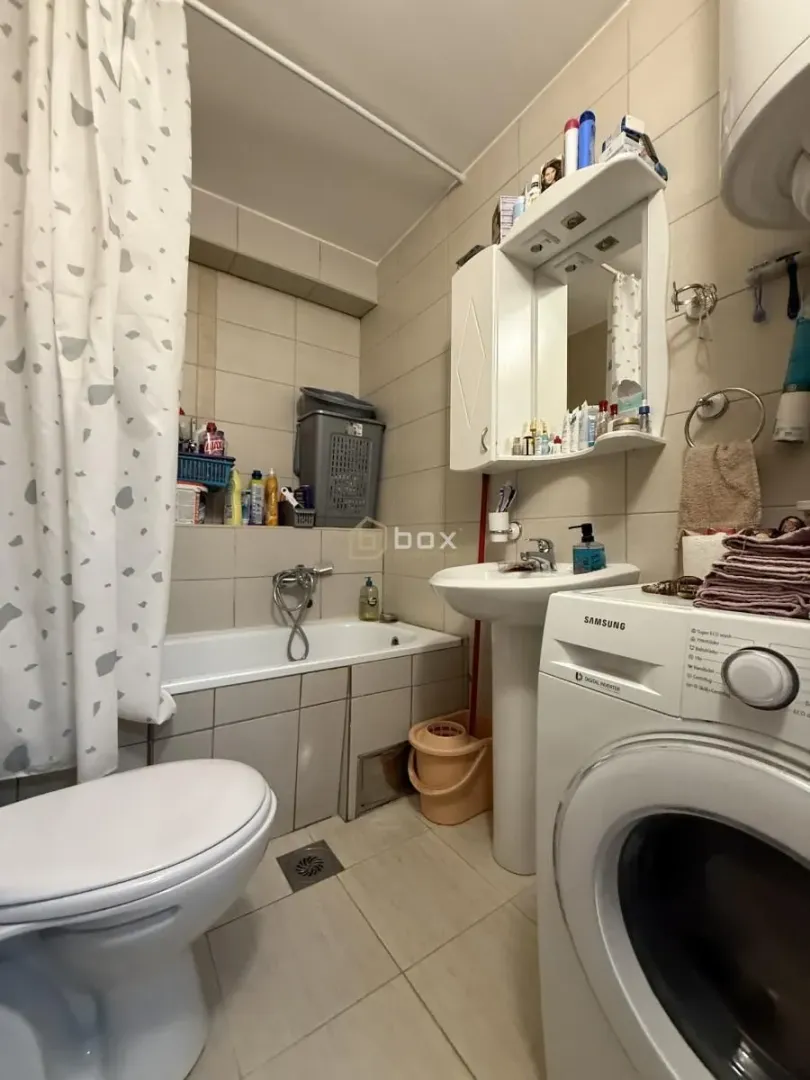 Kupatilo opremljeno kadom, umivaonikom, veš mašinom i wc šoljom.