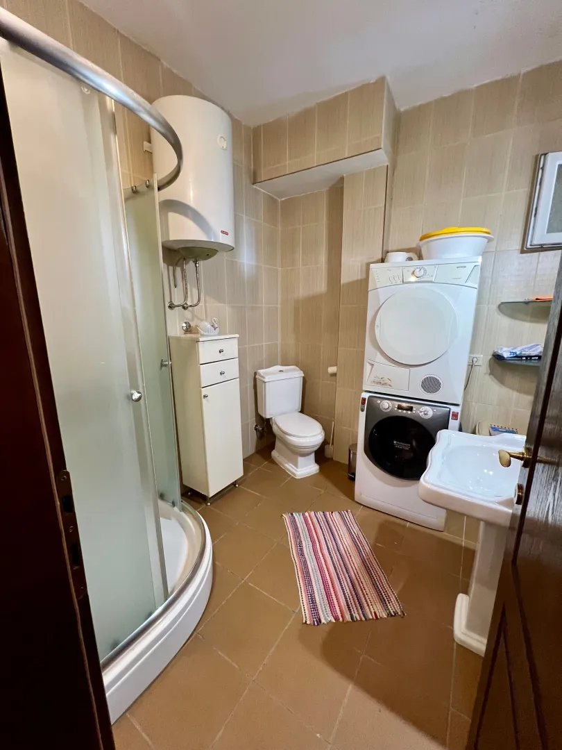 Fully equipped bathroom with a shower cabin, toilet, sink, and washing machine.