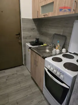 Small kitchen with wood-finish cabinets and a stove. - image 10