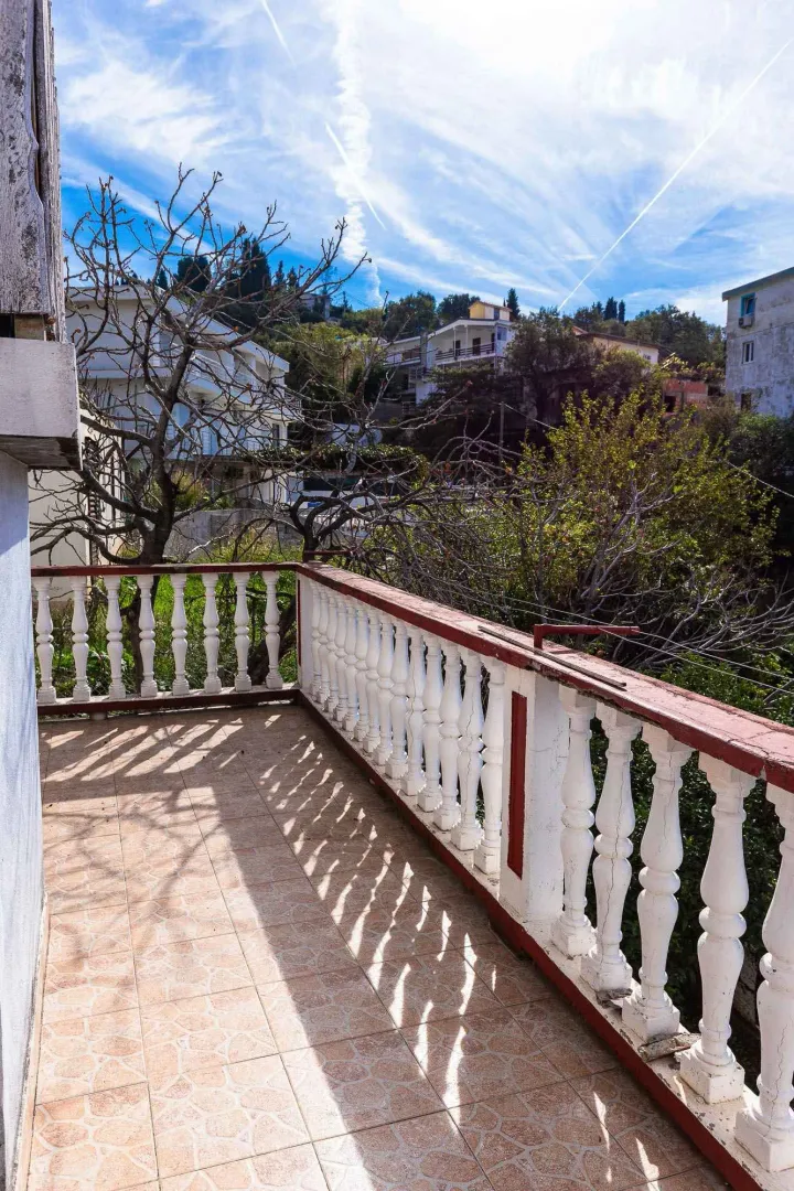 Prostrana terasa sa betonskom ogradom i pogledom na okolno naselje i zelenilo.